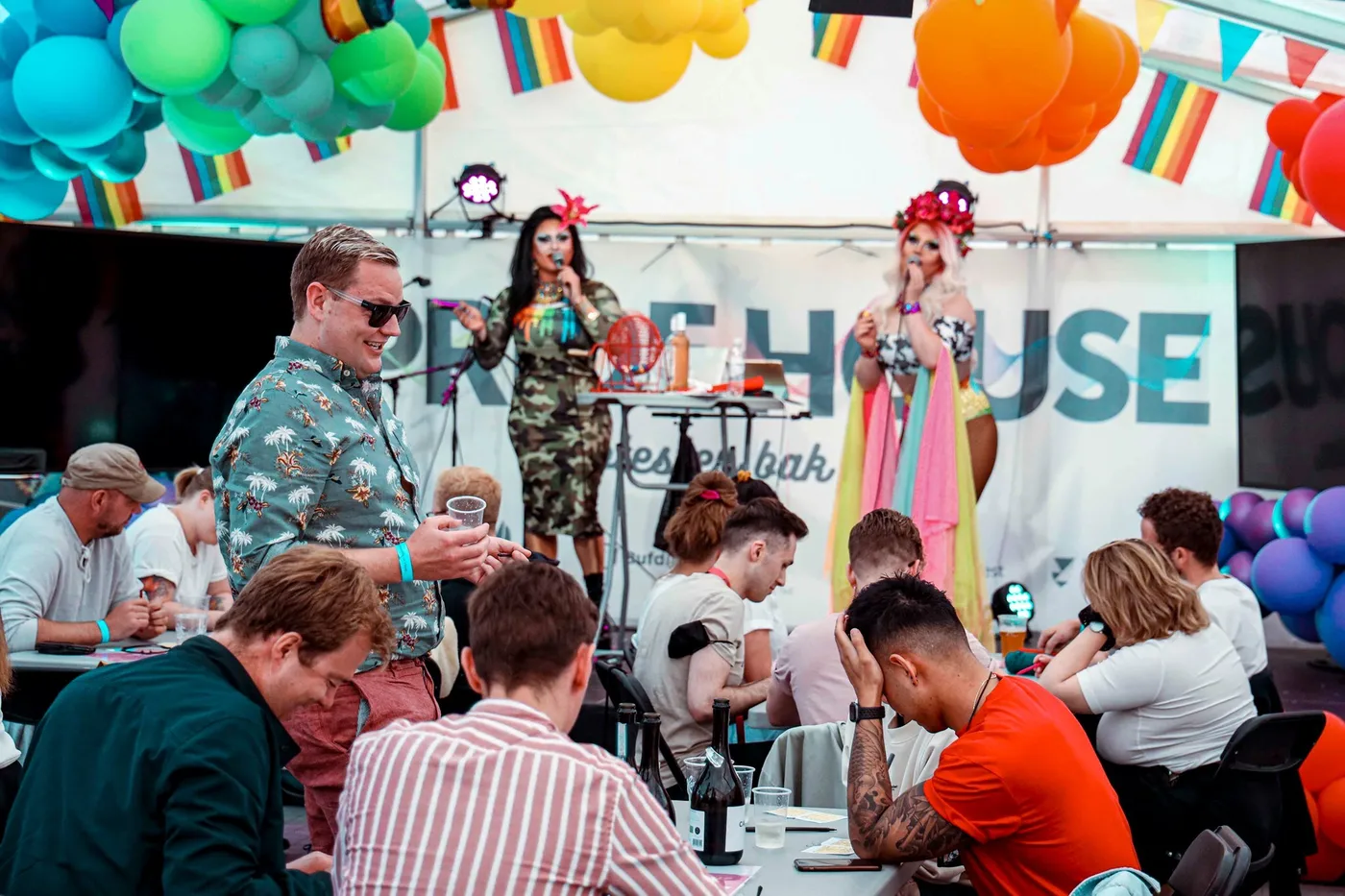 Dragartister på scenen og publikum ved bordene i Pride House